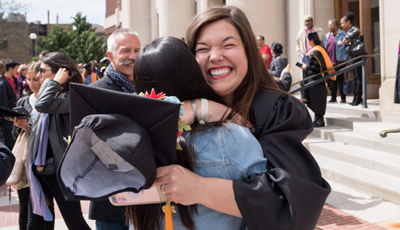 Student hugging a love one at graduation with a big smile on her face