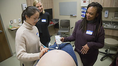 Three female students check up on a pregnant woman